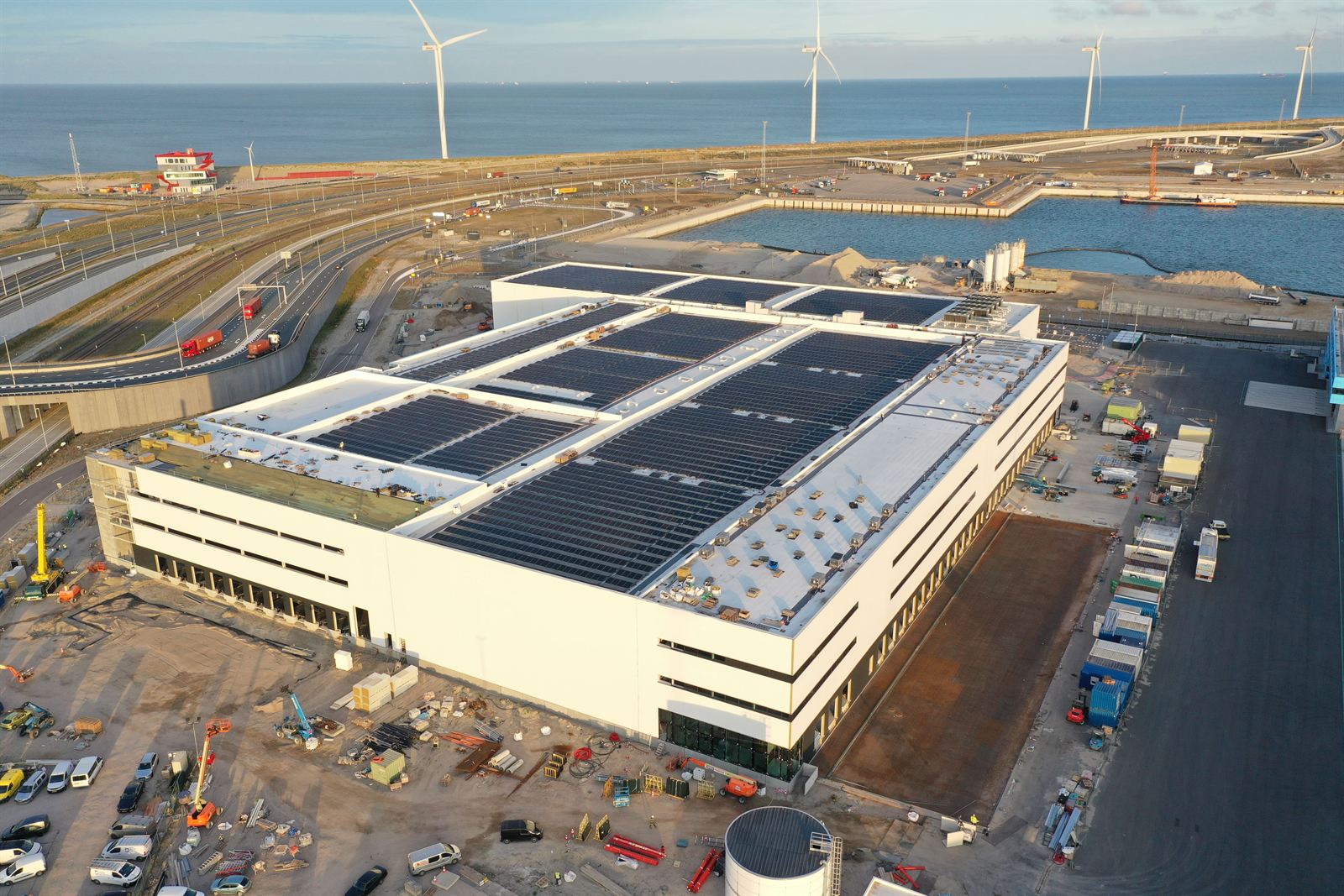 Luchtfoto van een distributiecentrum in aanbouw, met zonnepanelen op het dak