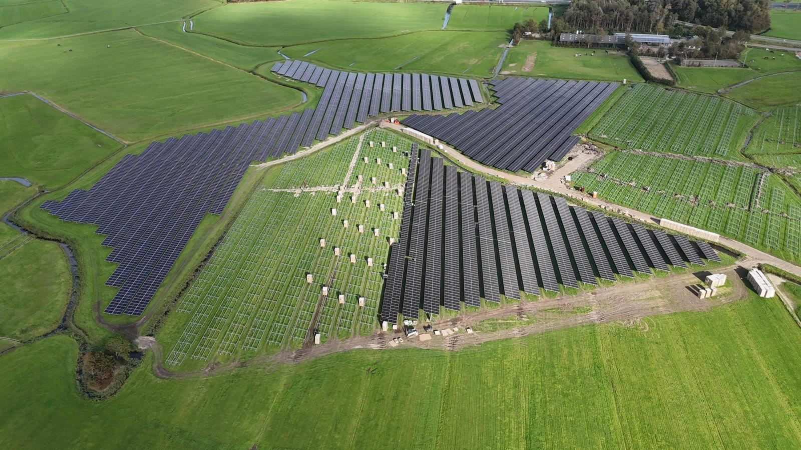 Luchtfoto van een zonnepark in aanbouw in een groen polderlandschap